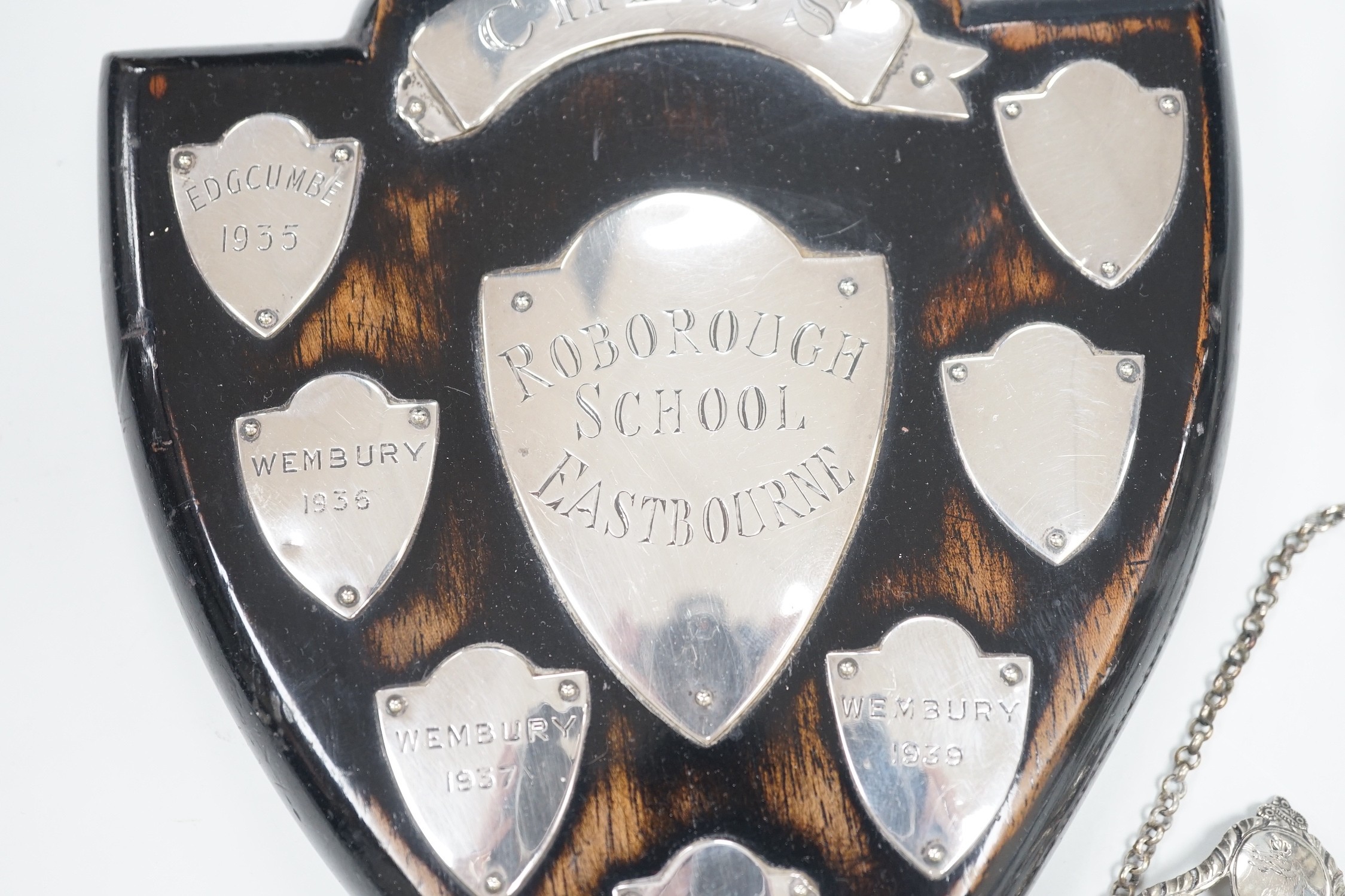 A small 1930's silver christening mug, two 19th century silver decanters labels 'Claret' and 'Marsala' and a white metal mounted polished wood shield 'Roborough School, Eastbourne Chess' and a Victorian silver oval musta